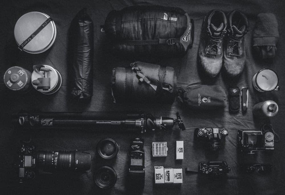 An outdoor backpack and gear laid out on a neutral surface