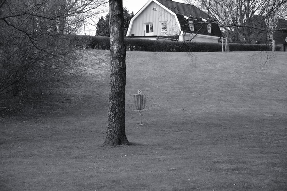 A disc golf practice basket standing on a garden lawn