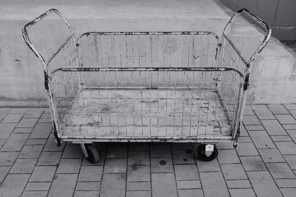 A wheeled cart standing on grass in flat, diffused light