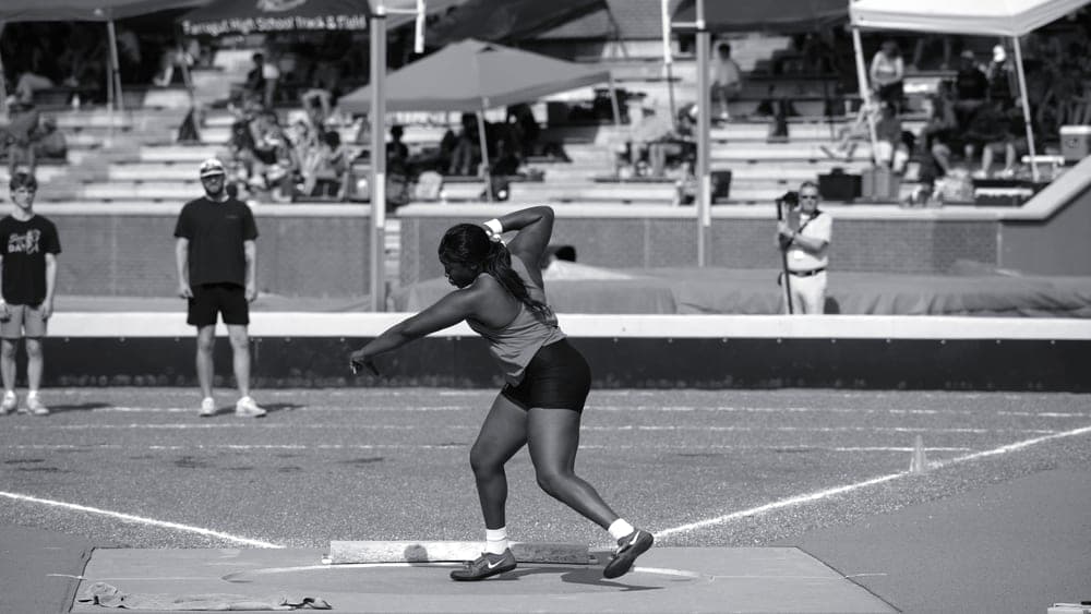 An athlete mid-throw, photographed from the side in an outdoor field