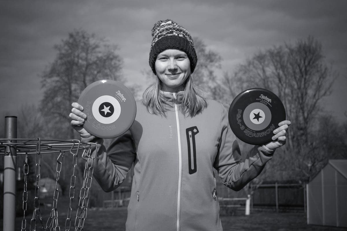 A player holding a small stack of disc golf discs outdoors in flat, diffused light