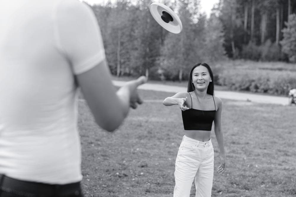 A player throwing a flying disc outdoors in a park in diffused light